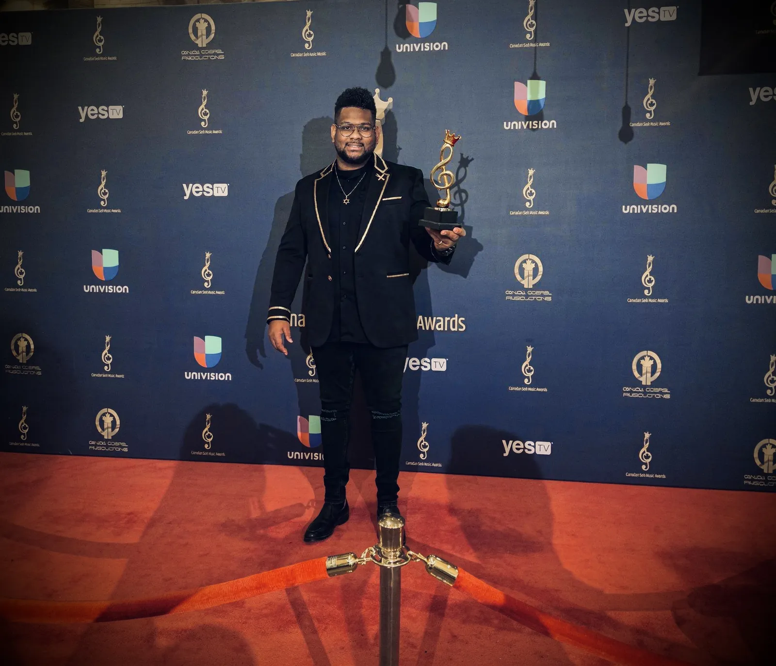 Joshua Ali on the red carpet holding his award