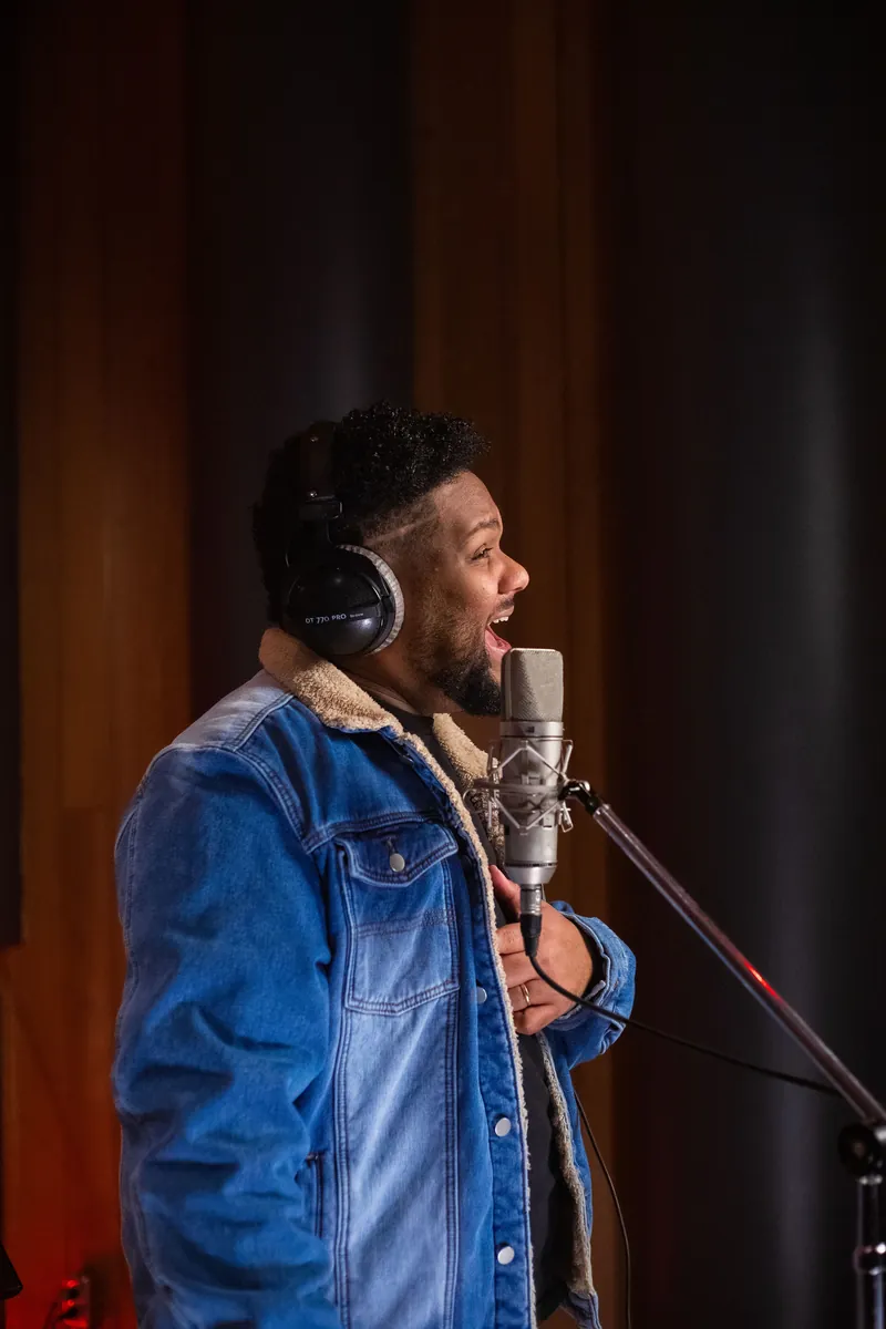 Joshua Ali singing at a studio microphone